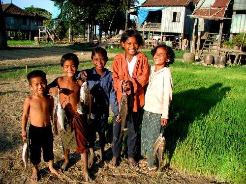 Kids holding fish along river bank in cambodia